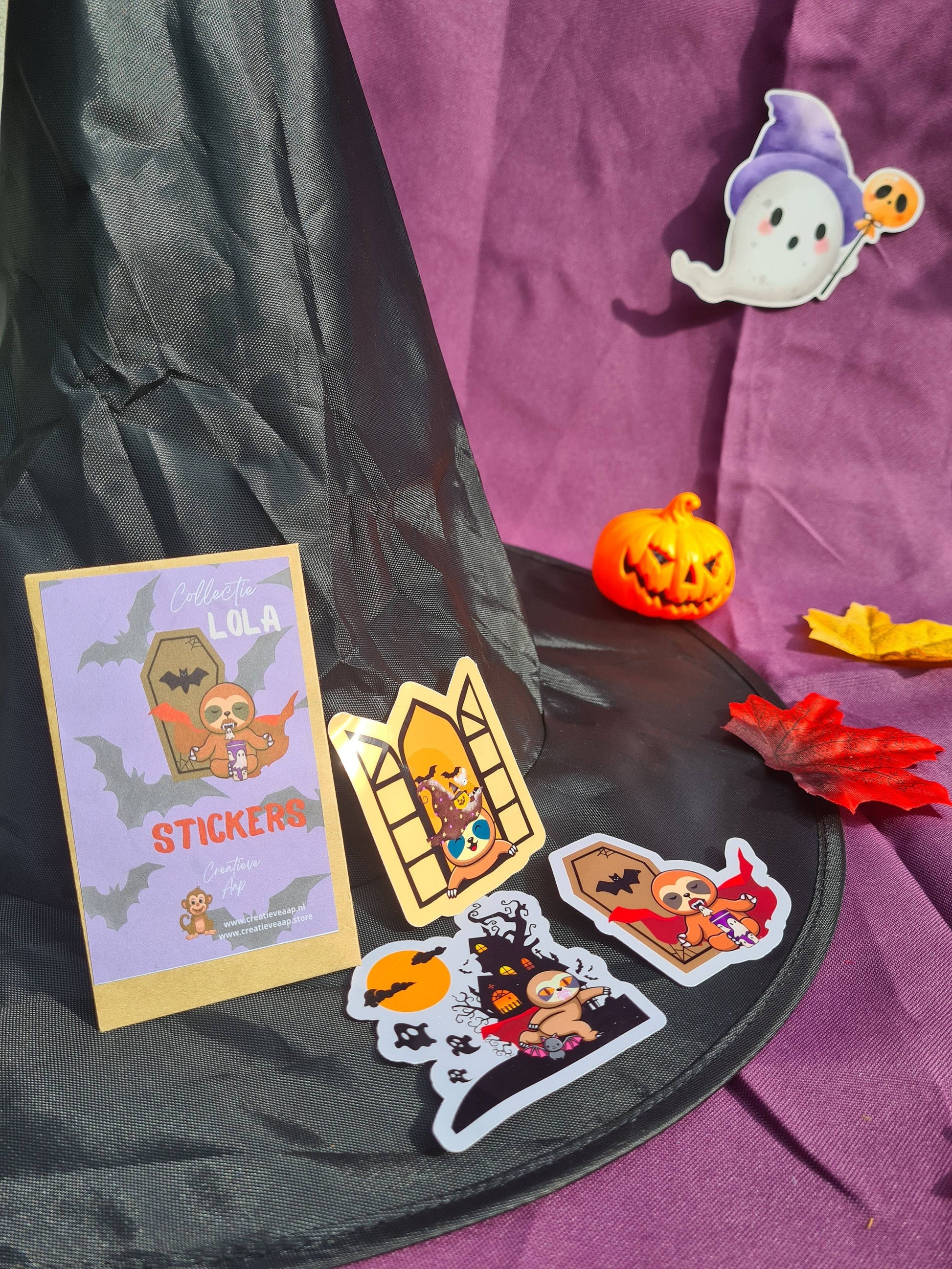 Vinylstickerset Collectie Lola de Luiaard met Halloween-thema, bestaande uit schattige luiaardstickers in verschillende Halloween-scenario's.