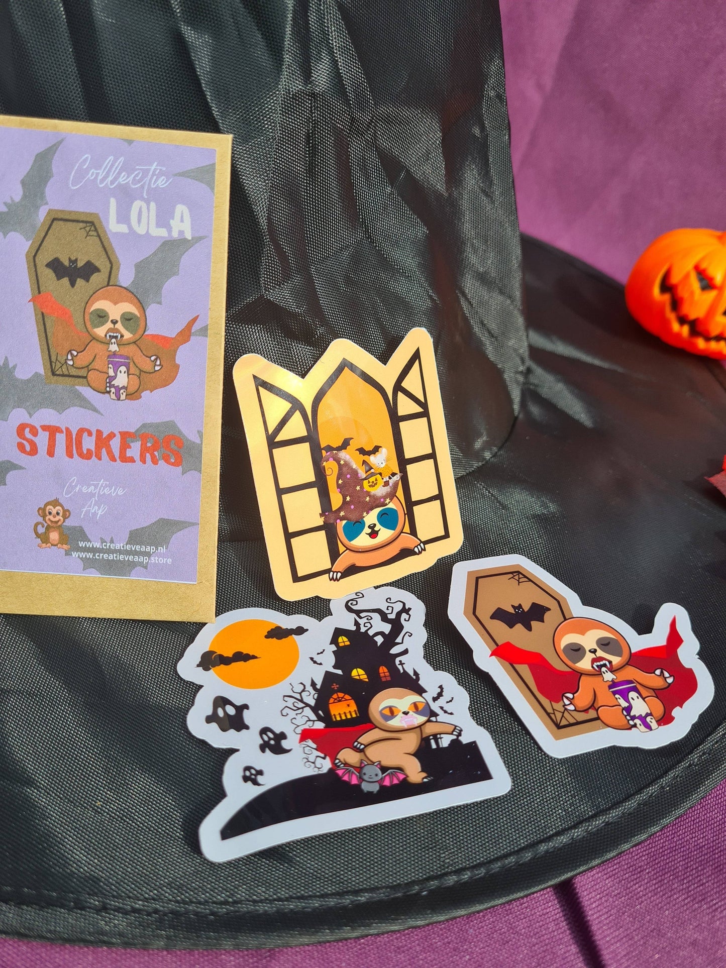 Vinylstickerset Collectie Lola de Luiaard met Halloween-thema, bestaande uit schattige luiaardstickers in verschillende Halloween-scenario's.